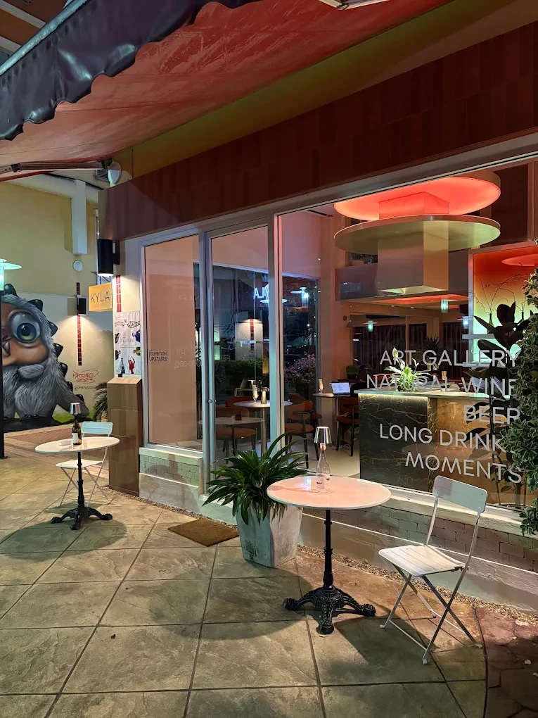 KYLA's storefront at night, with window lettering for the art gallery and natural wine bar